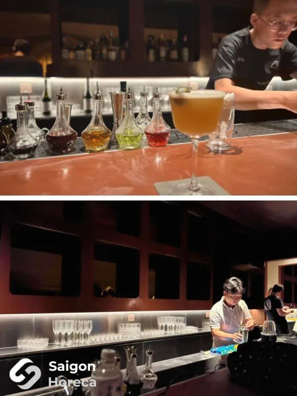 Bartender crafting cocktails at the copper-clad bar counter with decanters and illuminated back-bar glassware shelving at Bambino