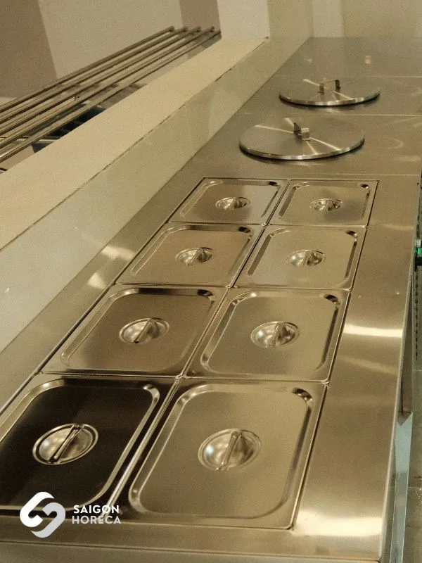 Row of stainless steel Gastronorm (GN) pans with lids arranged along the serving pass at the Sheh Fung canteen