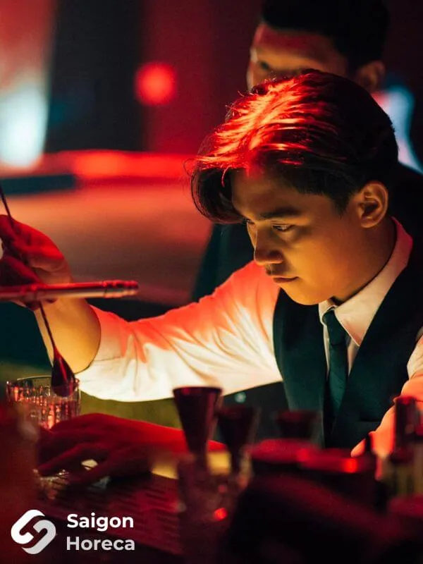 Professional mixologist in vest and shirt crafting artisanal cocktails at Bling Bling Club’s bar station