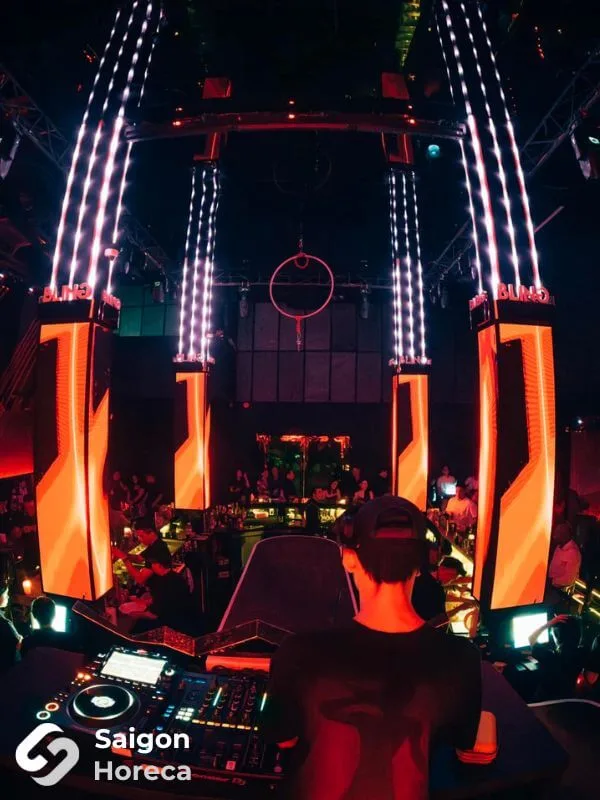 Live DJ performance booth framed by intense amber and crimson LED columns at Bling Bling Club