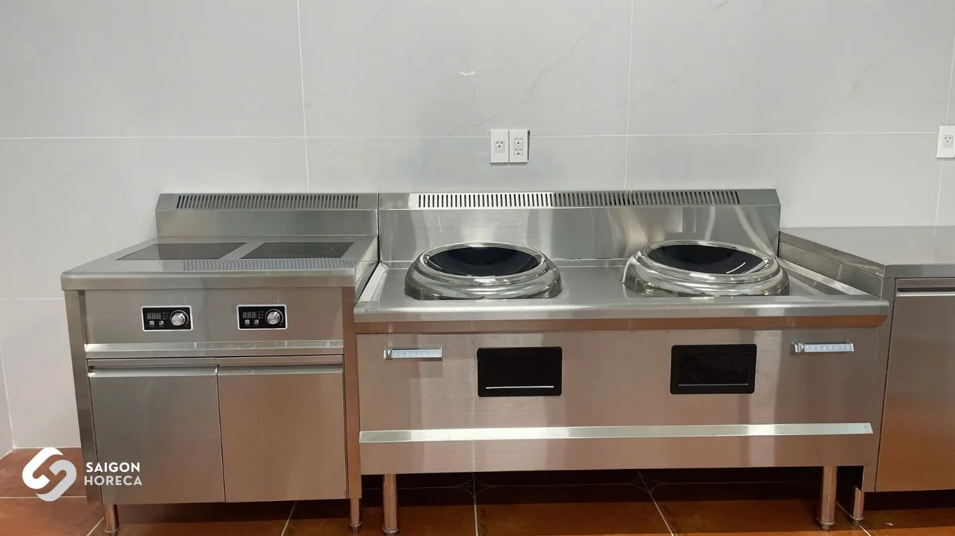 Heavy-duty commercial stainless steel induction wok cooking line at Vinh Hiep facility engineered by Saigon Horeca