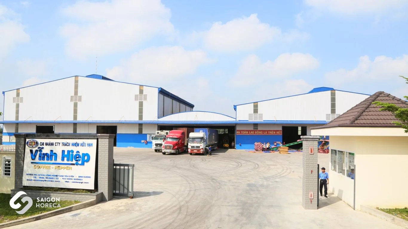 Main gate and facade of Vinh Hiep coffee factory with container trucks loading export shipments