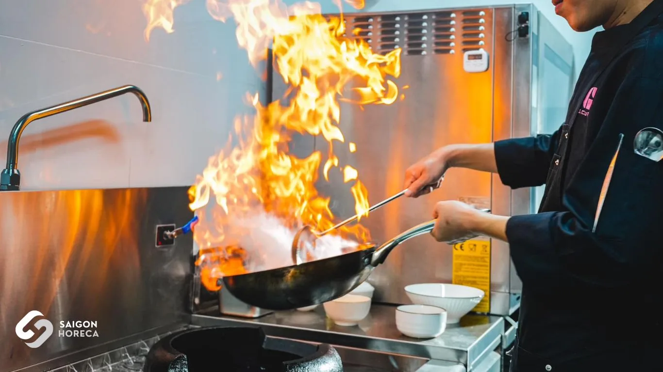 Chef performing high-flame wok cooking on commercial Asian gas range at G-Cup Bistro