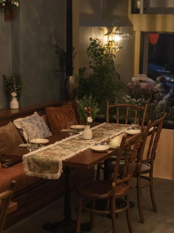 Cozy seating nook with timber banquettes and floral table runners—where patrons savor handcrafted European pastries