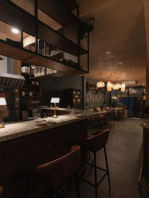 Terrazzo counter bar and cozy dining tables seamlessly blended beneath warm woven rattan pendant lighting