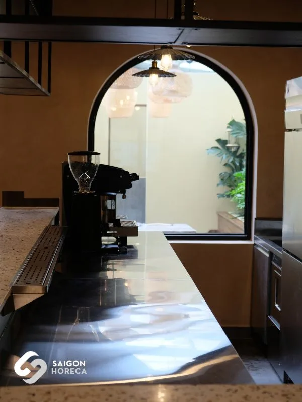 Stainless steel barista station with commercial coffee grinder framed by an arched opening—compactly organized for narrow spaces