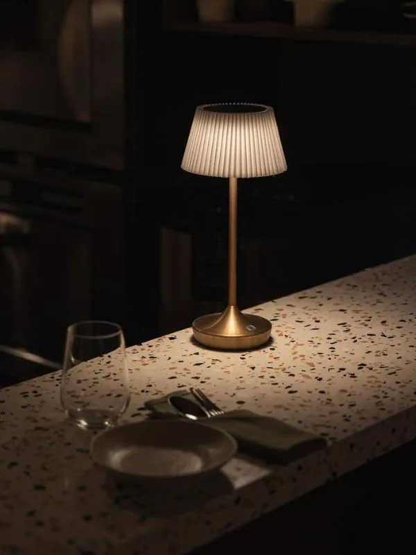 Close-up of the terrazzo tabletop accented with brushed gold lamps and bespoke cutlery—details cultivating an intimate ambiance