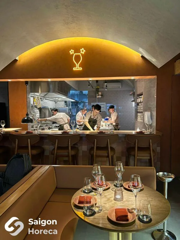 Round dining table overlooking the arched open kitchen with the glowing neon wine glass at Little Bear Thao Dien