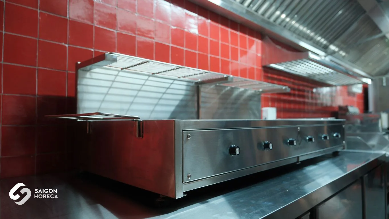 Linear commercial stainless steel cooking range with overhead plate warming shelves and red brick tiling engineered by Saigon Horeca at Mam Mam