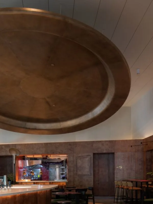 Mam Mam lounge interior: elliptical copper acoustic ceiling feature, curved cocktail bar, and stainless steel open kitchen viewed through the pass-through window