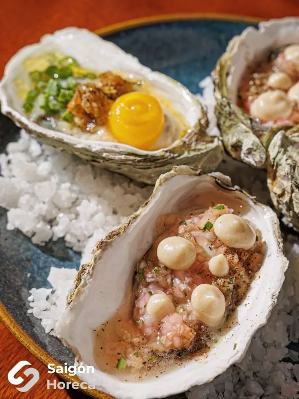 Grilled oysters served on coarse sea salt rock at Mùa Craft Sake