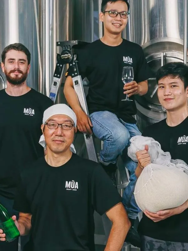 The Mùa Craft Sake brewing team alongside stainless steel fermentation tanks