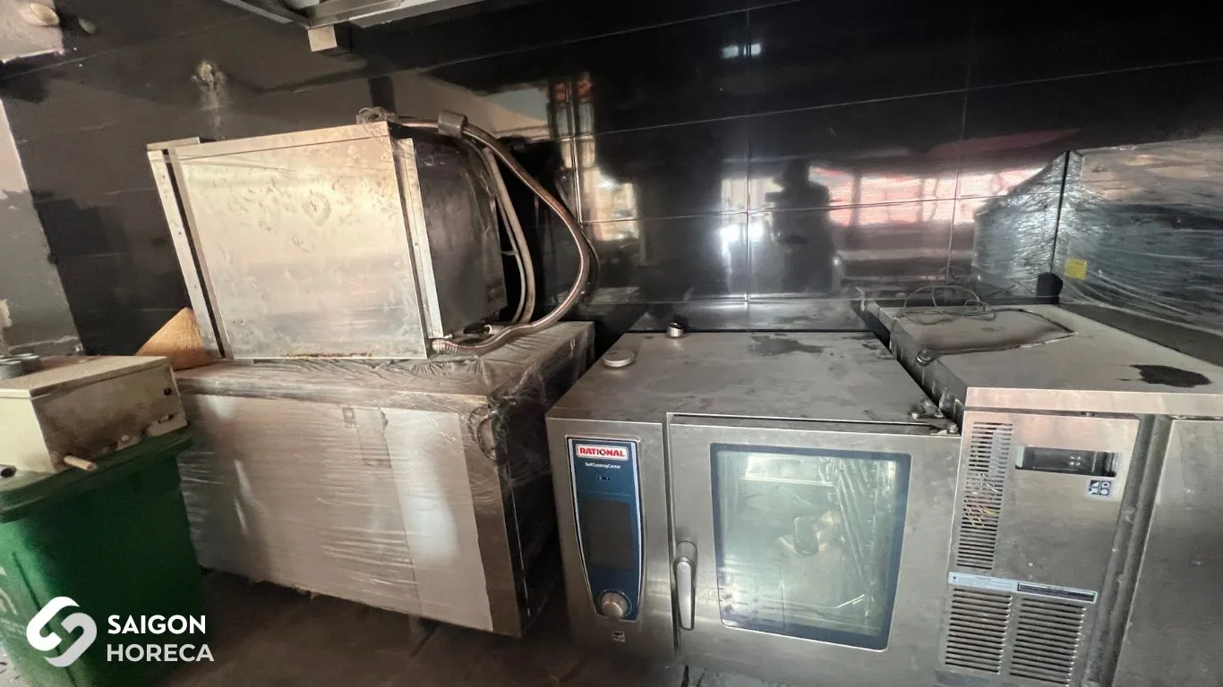 Equipment assembly phase at Sol Kitchen & Bar District 7: RATIONAL combi oven, stainless steel cabinets, and chillers positioned against black tiled walls.