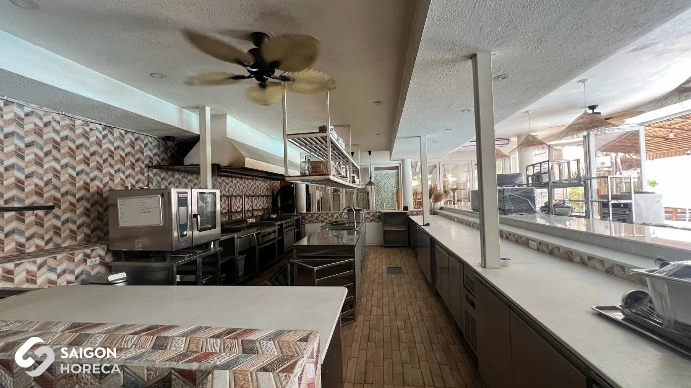 Original restaurant space prior to renovation at Sol Kitchen & Bar District 7: patterned upholstered seating area, ceiling fans, and legacy stainless steel kitchen line in the back.