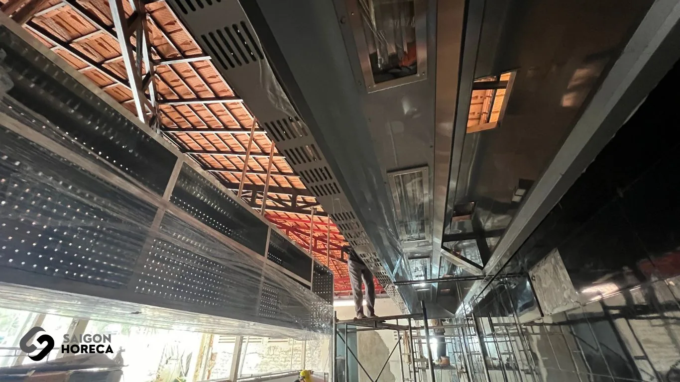 Installation of long overhead stainless steel exhaust ductwork along ceiling at Sol Kitchen & Bar District 7 kitchen site.
