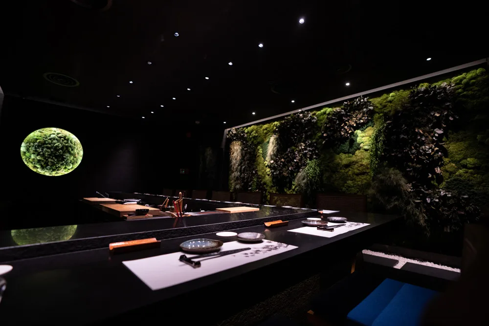 Roka Fella Omakase sushi counter ambiance enveloped by living green moss wall.
