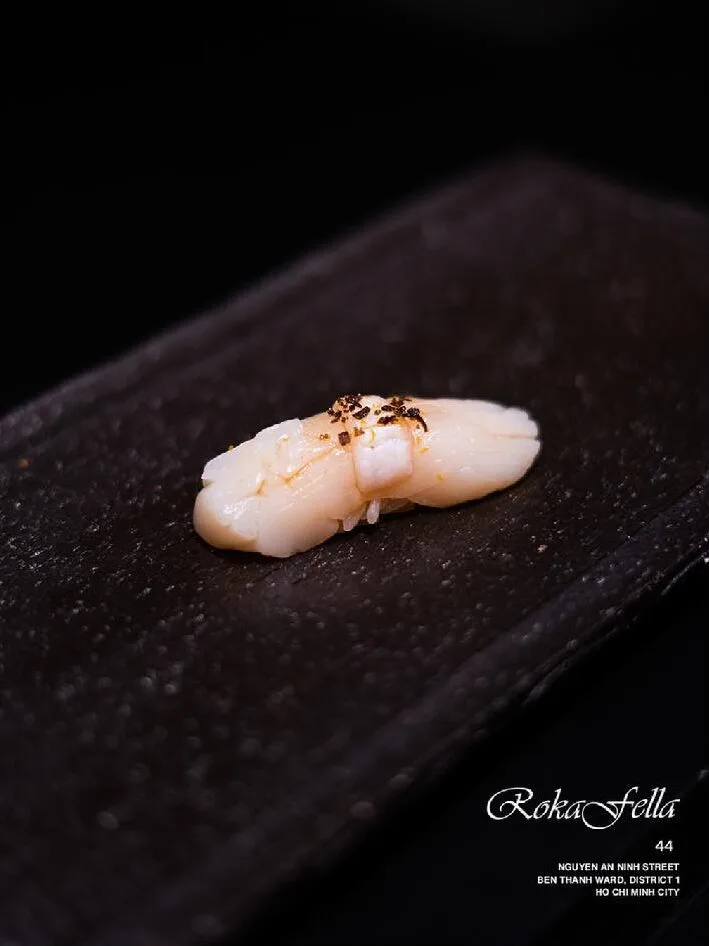 Aburi flame-kissed Hotate scallop nigiri dusted with freshly cracked black pepper at Roka Fella.