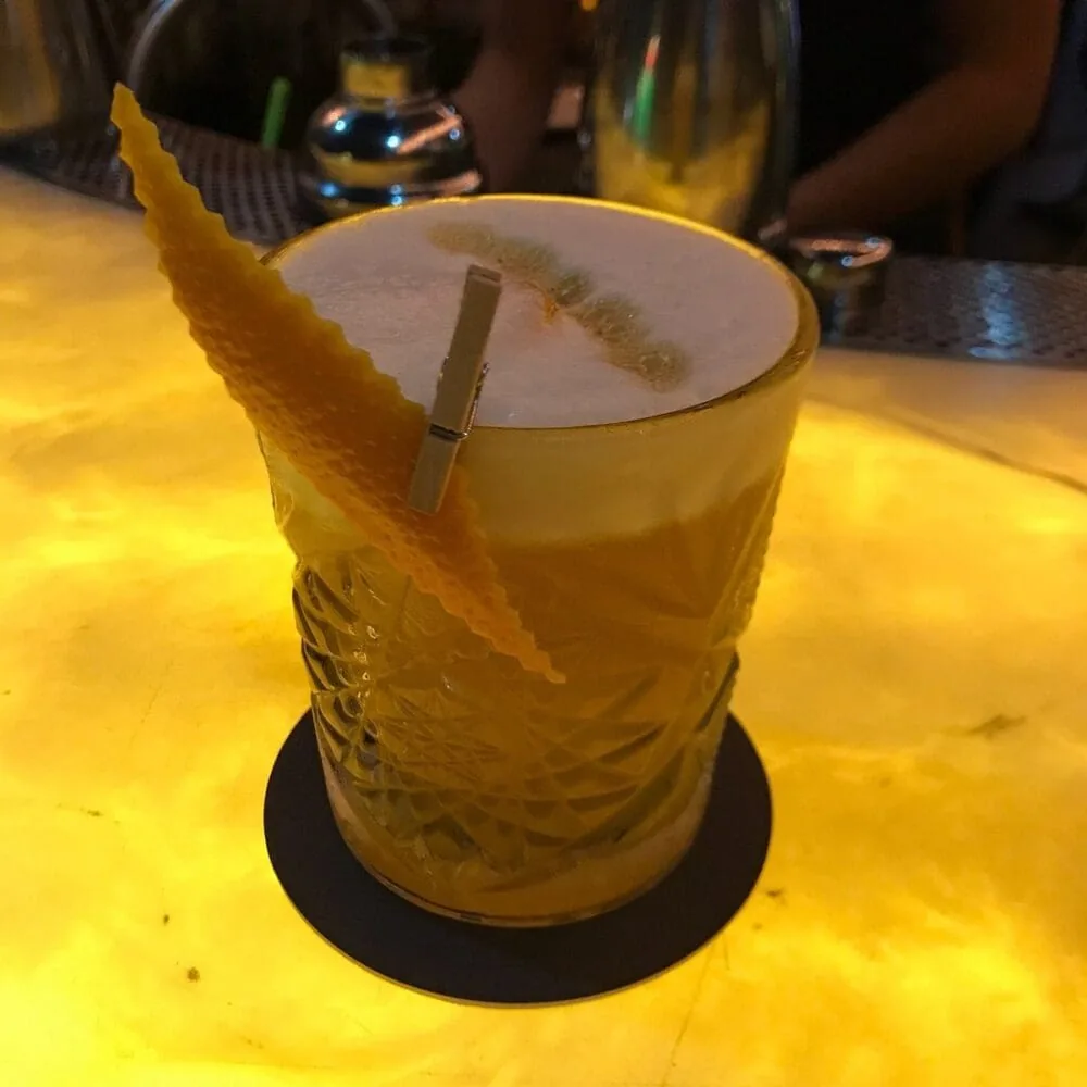 Vibrant citrus cocktail resting on luminous backlit stone at Skyloft by Glow.