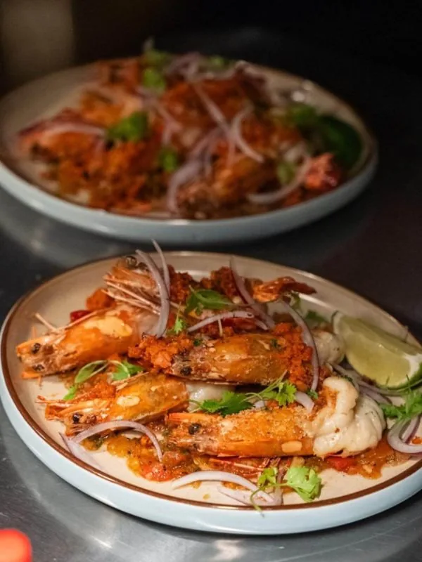 Whole tiger prawns simmered in tomato-chili sofrito sauce, garnished with red shallots, coriander, and fresh lime at Sol Kitchen & Bar