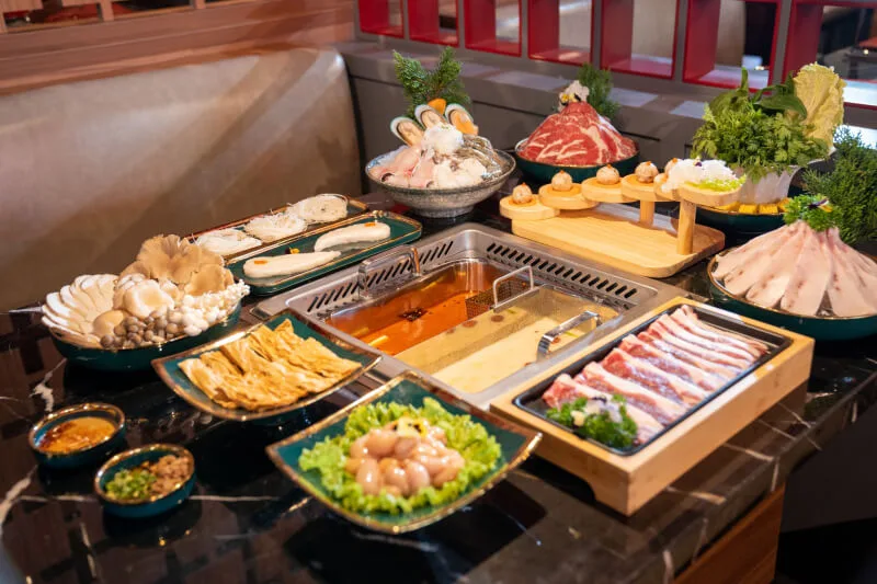 Sichuan hotpot feast featuring dual-flavor stainless steel pot, premium beef cuts, fresh seafood, and garden greens