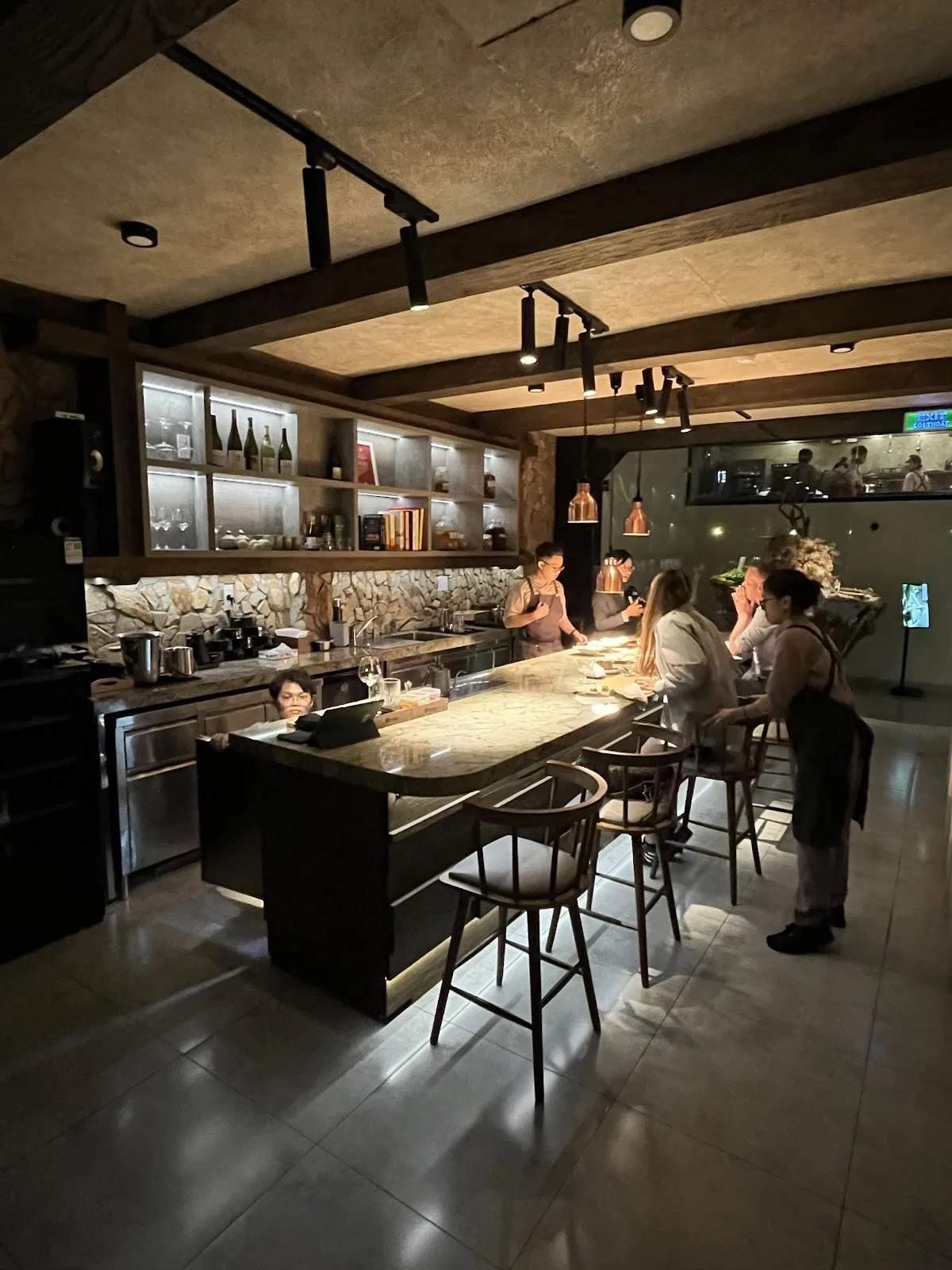 Marble-topped cocktail bar with counter seating, overlooking an open theater kitchen