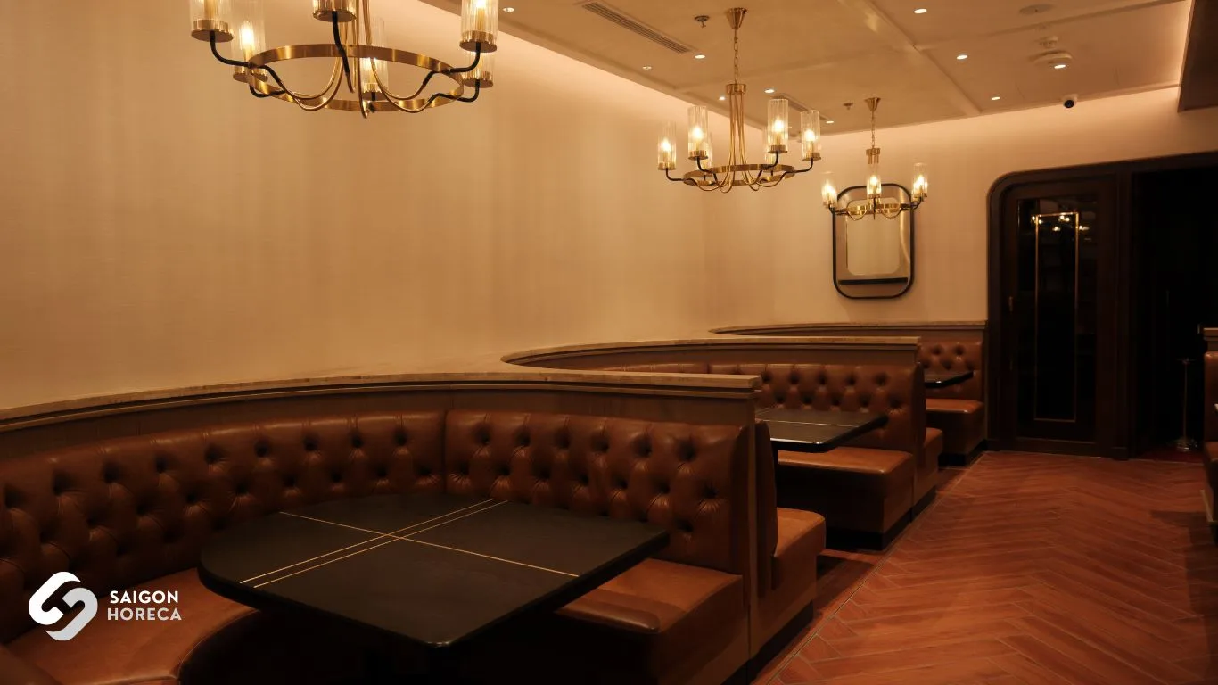 Warm brown leather banquette seating beneath classic chandeliers at The Royal
