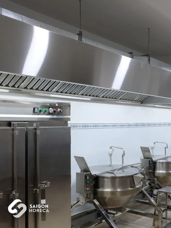 Stainless steel commercial rice steamer and tilting kettle battery under large-format exhaust hood