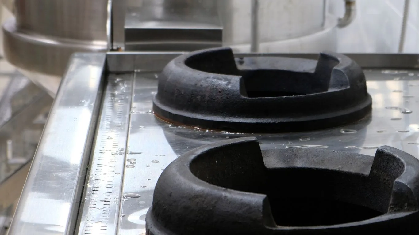 Close-up of heavy-duty cast iron gas burners engineered on commercial stainless steel cooktop