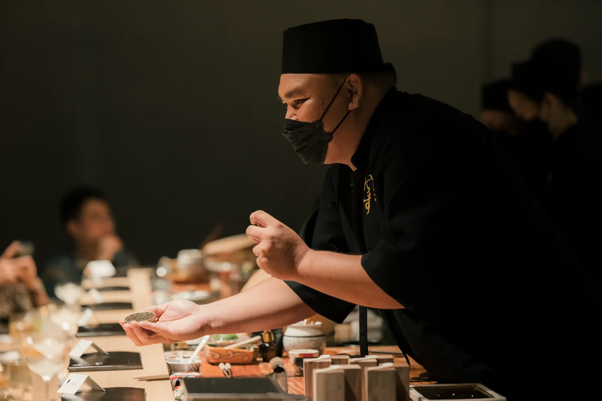 Executive chef personally presenting the prestige tin of royal caviar to counter guests